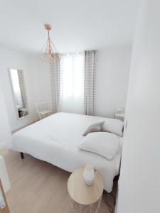 Dormitorio blanco con cama y mesa en L'Escale cocooning T3 Centre ville, en Bagnères-de-Bigorre