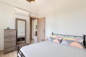 Schlafzimmer mit einem Bett, einer Kommode und einem Spiegel in der Unterkunft Dimitra's sunny villa in Mirsinokhórion