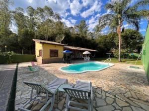 a backyard with a pool and chairs and a house at Casa de Campo em Penedo - RJ in Itatiaia