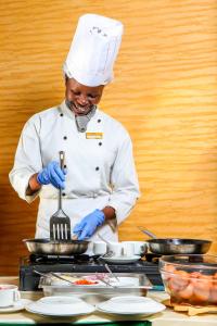 uno chef tiene una forchetta in padella di Weston Hotel a Nairobi