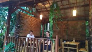 two men sitting on a porch of a building at Pondok rinjani bungalow tetebatu in Tetebatu