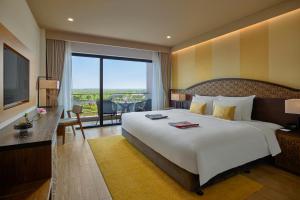 a hotel room with a large bed and a balcony at KOBI Onsen Resort Hue in Hue