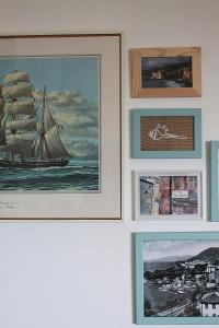 een rij ingelijste foto's aan een muur met een zeilboot bij MareNostrum in Pieve Ligure