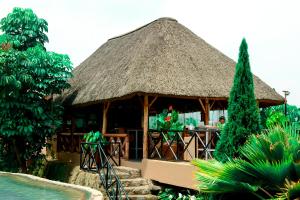 une grande cabane avec un toit en gazon à côté d'une piscine dans l'établissement Kim Hotel, à Kigali