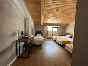 a room with three beds and a desk and a table at Capra Hotel Kazbegi in Stepantsminda