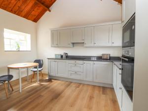 una cocina con armarios blancos y una mesa con sillas. en Wren cottage, en Sandbach