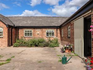 a brick house with a garage and flowers at Wren cottage in Sandbach