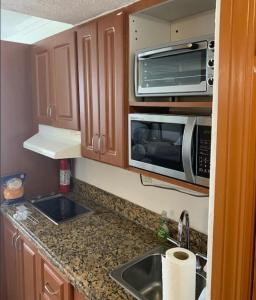 a small kitchen with a sink and a microwave at Ramada Marco Polo Beach in Miami Beach