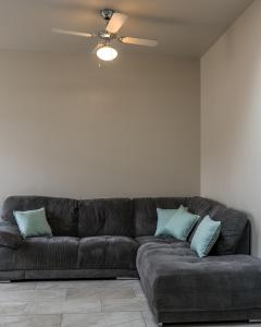 Sofá marrón en la sala de estar con ventilador de techo en Parke -HotTub- Apartment, en Pembroke Dock