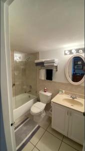 a bathroom with a toilet and a tub and a sink at Ramada Marco Polo Beach in Miami Beach +7 photos