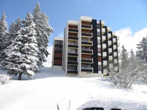 un bâtiment dans la neige avec des arbres enneigés dans l'établissement Appartement Chamrousse, 3 pièces, 8 personnes - FR-1-549-70, à Chamrousse