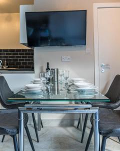 una mesa de cristal con sillas y platos. en Parke -HotTub- Apartment, en Pembroke Dock