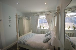 a bedroom with a canopy bed and two windows at Sandridge in Newbiggin-by-the-Sea