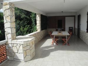un patio con una mesa y una pared de piedra en Apartments Vesna G., en Šilo