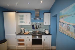 kuchnia z białymi szafkami i niebieską ścianą w obiekcie Sandridge w mieście Newbiggin-by-the-Sea