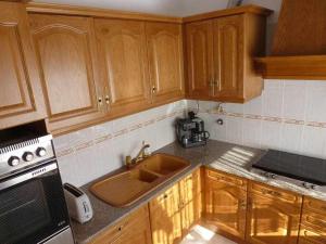a kitchen with wooden cabinets and a sink at Quinta dos Brazilaves - Ponte de Lima in Ponte de Lima