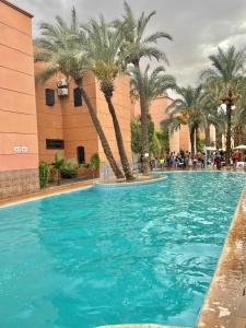 una gran piscina con palmeras frente a un edificio en Riad Lyna en Marrakech