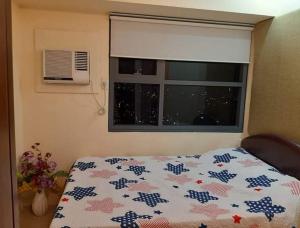 宿务Horizons 101 Condominium Cebu City near Malls的卧室配有一张床、一条被子和一扇窗户