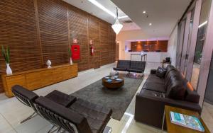 sala de estar con muebles de cuero y puerta roja en Fusion Acomodação Particular na Asa Norte ao Lado do SHOPPING CONJUNTO NACIONAL com Garagem - 7º andar, en Brasilia