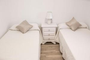 2 aparte bedden in een kamer met een nachtkastje bij El Rincón de Soraya in Sanlúcar de Barrameda