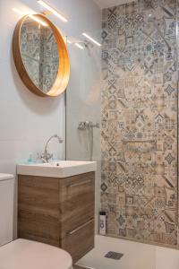 een badkamer met een wastafel en een douche met een spiegel bij El Rincón de Soraya in Sanlúcar de Barrameda