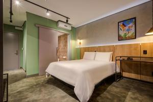 a bedroom with a large white bed and green walls at Slaviero Ponta Grossa in Ponta Grossa