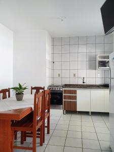 a kitchen with a table and chairs and a refrigerator at Pousada Figueira in Guarda do Embaú