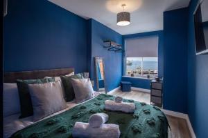 a blue bedroom with a bed with a green blanket at Ocean View Apartments - Mayfair in Blackpool