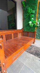 un banc en bois assis devant un mur vert dans l'établissement Villa Private Pool Syariah Musim Liburan, à Batu