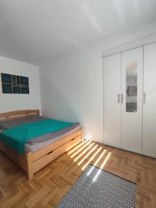 ein Schlafzimmer mit einem Bett, einem Kleiderschrank und einem Teppich in der Unterkunft Apartman Buda in Lukavica