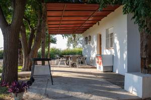un patio con una pérgola de madera y una mesa en Preciosa y confortable casa de campo con piscina y chimenea en Carmona