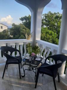 einen Balkon mit 2 Stühlen und einem Tisch mit Blumen darauf in der Unterkunft Hill view Vacational Rental in Runaway Bay