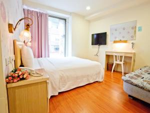 Dormitorio con cama, escritorio y TV en Green Park Commercial Hotel, en Tainan