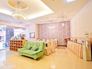 a waiting room with a green chair and a table at Green Park Commercial Hotel in Tainan