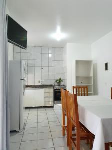 een keuken met een tafel en stoelen en een koelkast bij Pousada Figueira in Guarda do Embaú