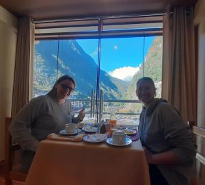 dos mujeres sentadas en una mesa frente a una ventana en Hs Tierra In, en Machu Picchu