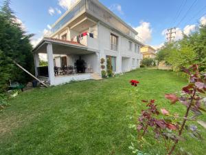 a large white house with a yard with a green lawn at Wonderful Villa Airport 5 minutes in Arnavutköy