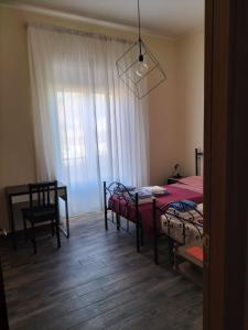 1 dormitorio con 2 camas, mesa y ventana en Core City Salerno, en Salerno