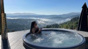 a woman sitting in a jacuzzi tub with a view at Rest Hub in Slavske