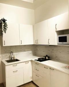 a kitchen with white cabinets and a sink and a microwave at Benny's Rooms Brussels City Centre in Brussels