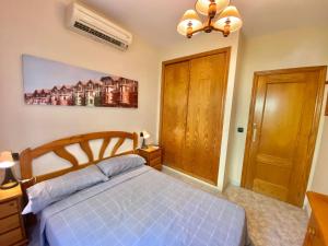 1 dormitorio con cama azul y puerta de madera en Playa Flamenca Aparment, en Orihuela Costa