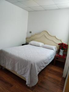 a bedroom with a bed with white sheets and flowers at Hotel Quilla House 2 in Urubamba