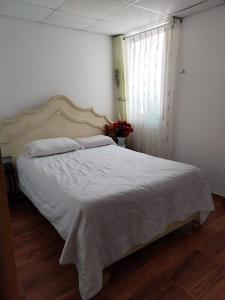 a bedroom with a large bed with white sheets and a window at Hotel Quilla House 2 in Urubamba