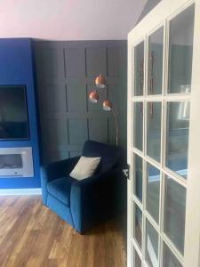 a living room with a blue chair and a lamp at Lovely 2 bedroom with private garden in Edinburgh