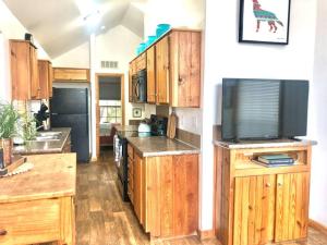 a kitchen with wooden cabinets and a flat screen tv at The Coyote Cabin - Cabins at Rim Rock in Austin