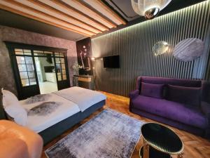 a bedroom with a bed and a purple couch at Alfa Luxury Boutique in Sibiu