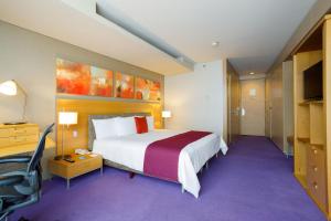 a hotel room with a large bed and purple carpet at Camino Real Santa Fe in Mexico City