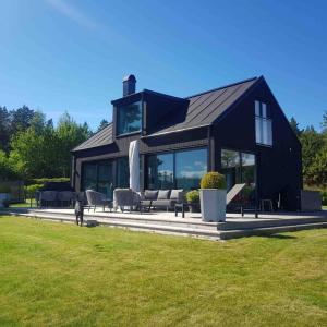 una casa negra con un perro parado en el césped en Stylish lake view house, en Vadstena