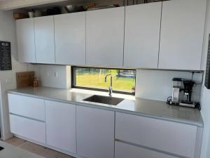 cocina blanca con fregadero y ventana en Stylish lake view house, en Vadstena