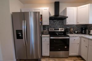 a kitchen with a stainless steel refrigerator and a stove at Pocono Lake Retreat - Relaxing 3bdm retreat w/ High Speed Wi-Fi, Work Space and Firepit in Pocono Lake